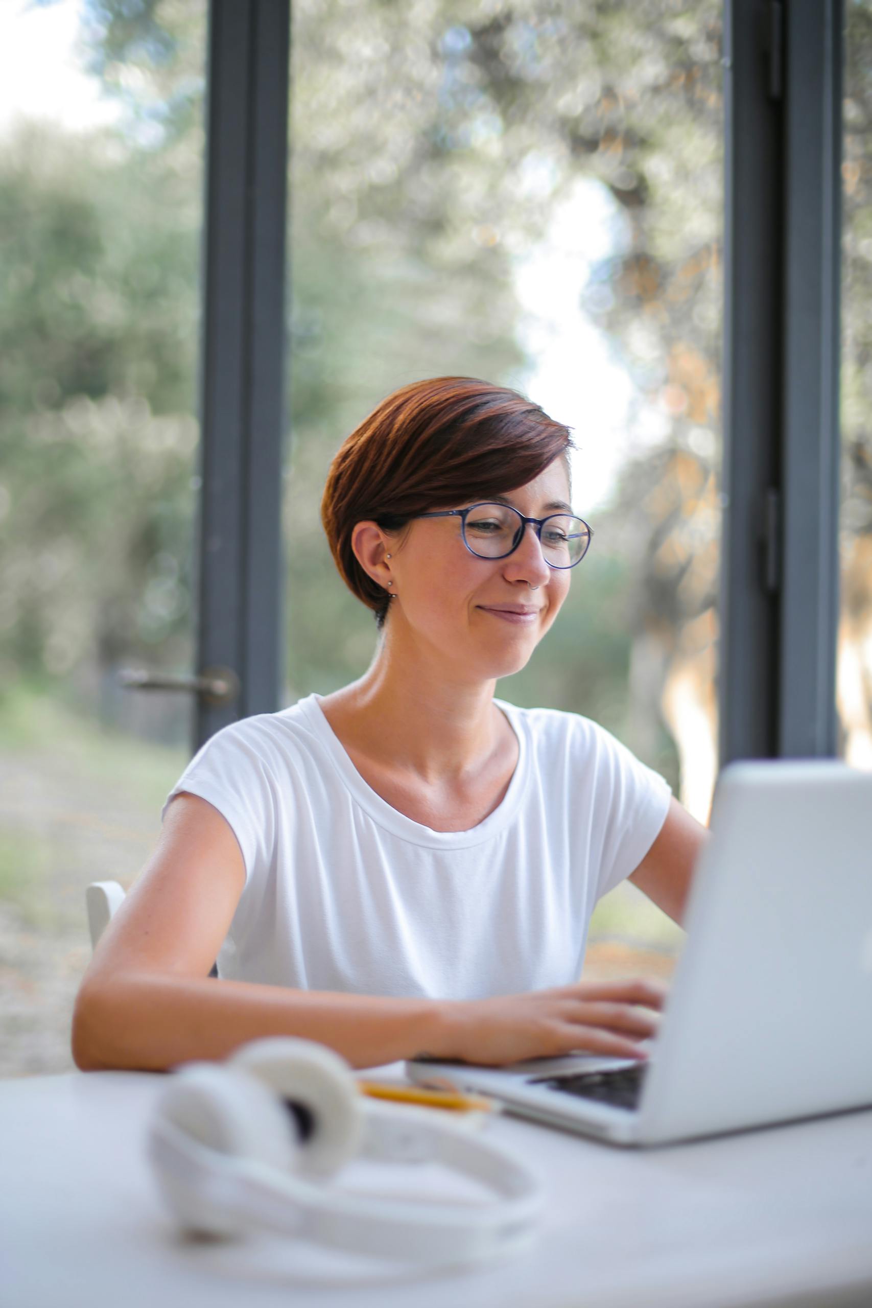 A happy woman with short hair using a laptop indoors, showcasing remote work lifestyle.